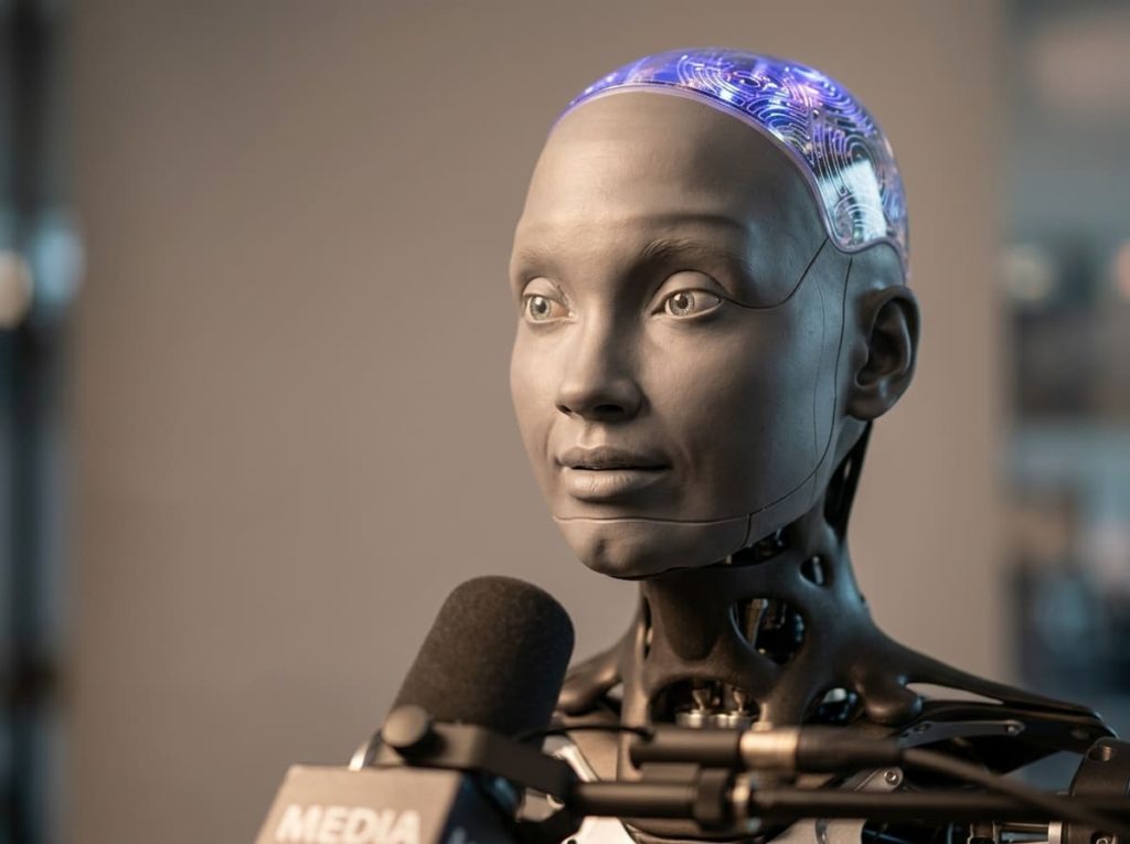 Close up of the Ameca humanoid robot during a recorded press interview.
